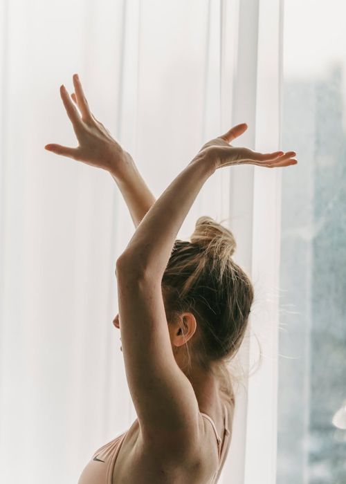A silhouette of a pregnant woman practicing a gentle yoga stretch.